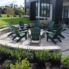 Outdoor patio with round fire pit, green Adirondack chairs, modern building. | Down To Earth Landscaping | Jackson New Jersey, USA (732) 833-7702