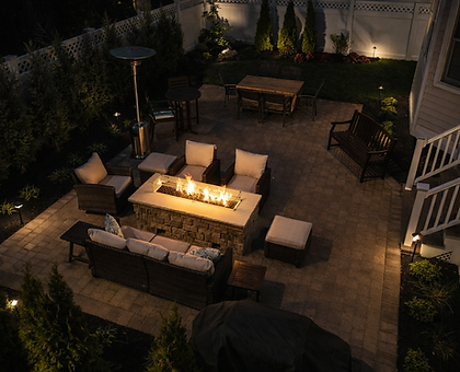 Cozy residential patio with lit fire pit and outdoor furniture at night.