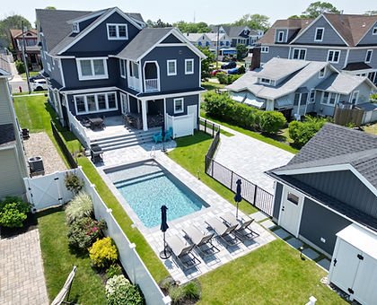 Large dark blue house with backyard swimming pool and lounge chairs.