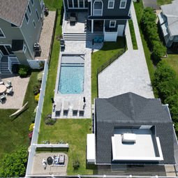 Overhead view: modern luxury home, swimming pool, spacious patio, and yard.