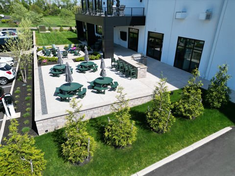 Outdoor patio with green picnic tables, umbrellas, next to modern building. | Down To Earth Landscaping | Jackson New Jersey, USA (732) 833-7702