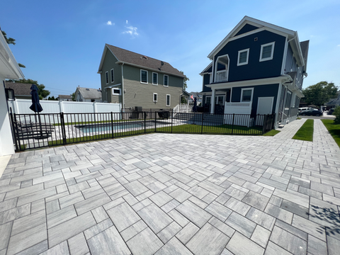 Spacious grey paver patio, fenced pool, green and blue residential homes. Residential landscaping near me| Down To Earth Landscaping | Jackson New Jersey, USA (732) 833-7702