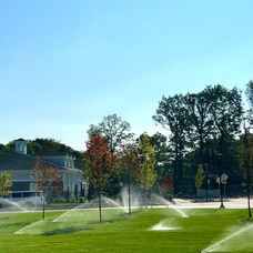 Sprinklers watering green lawn in a residential area on a sunny day. | Down To Earth Landscaping | Jackson New Jersey, USA (732) 833-7702